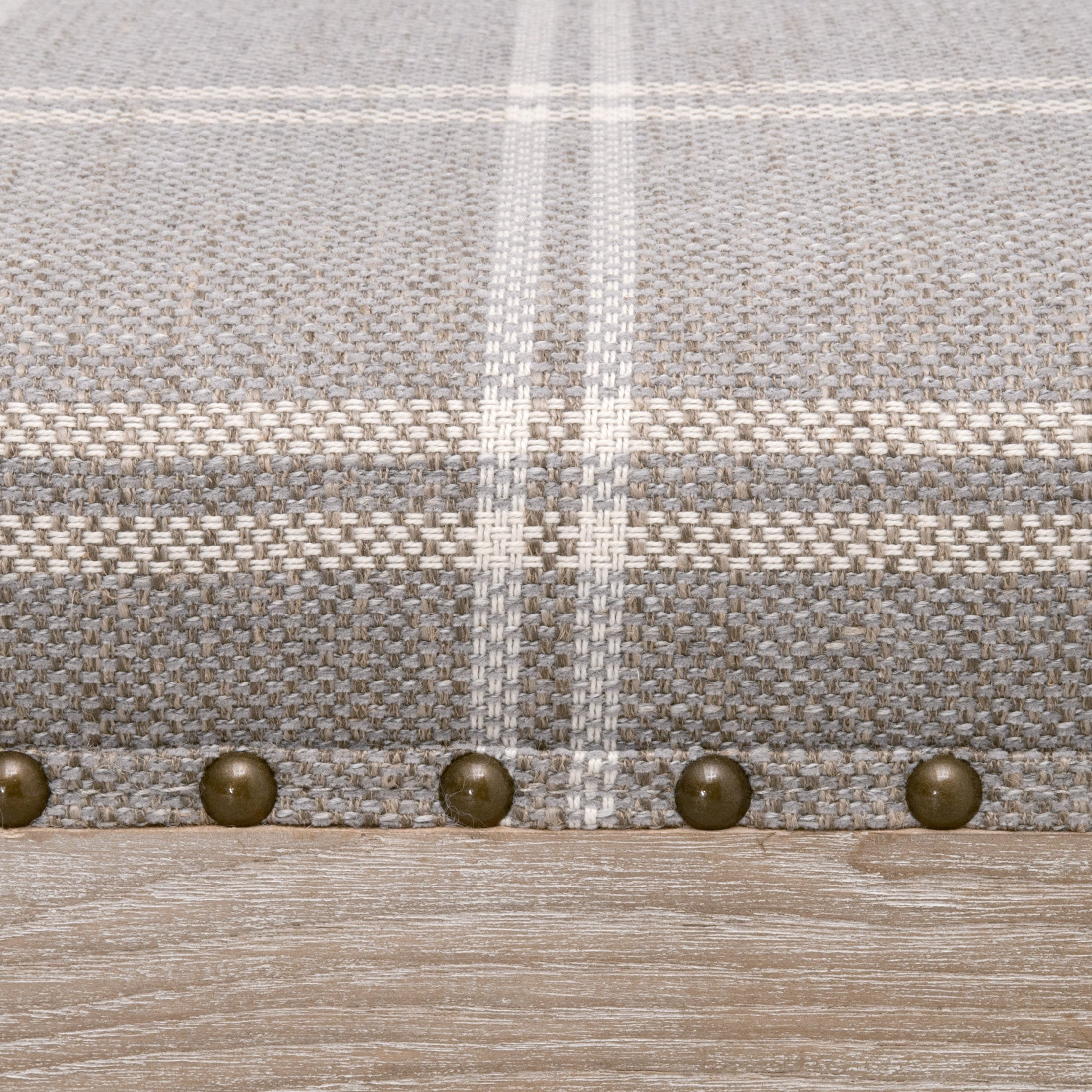 Close-up of Townsend Upholstered Coffee Table fabric with gray plaid pattern and gold nailhead trim on ash wood base