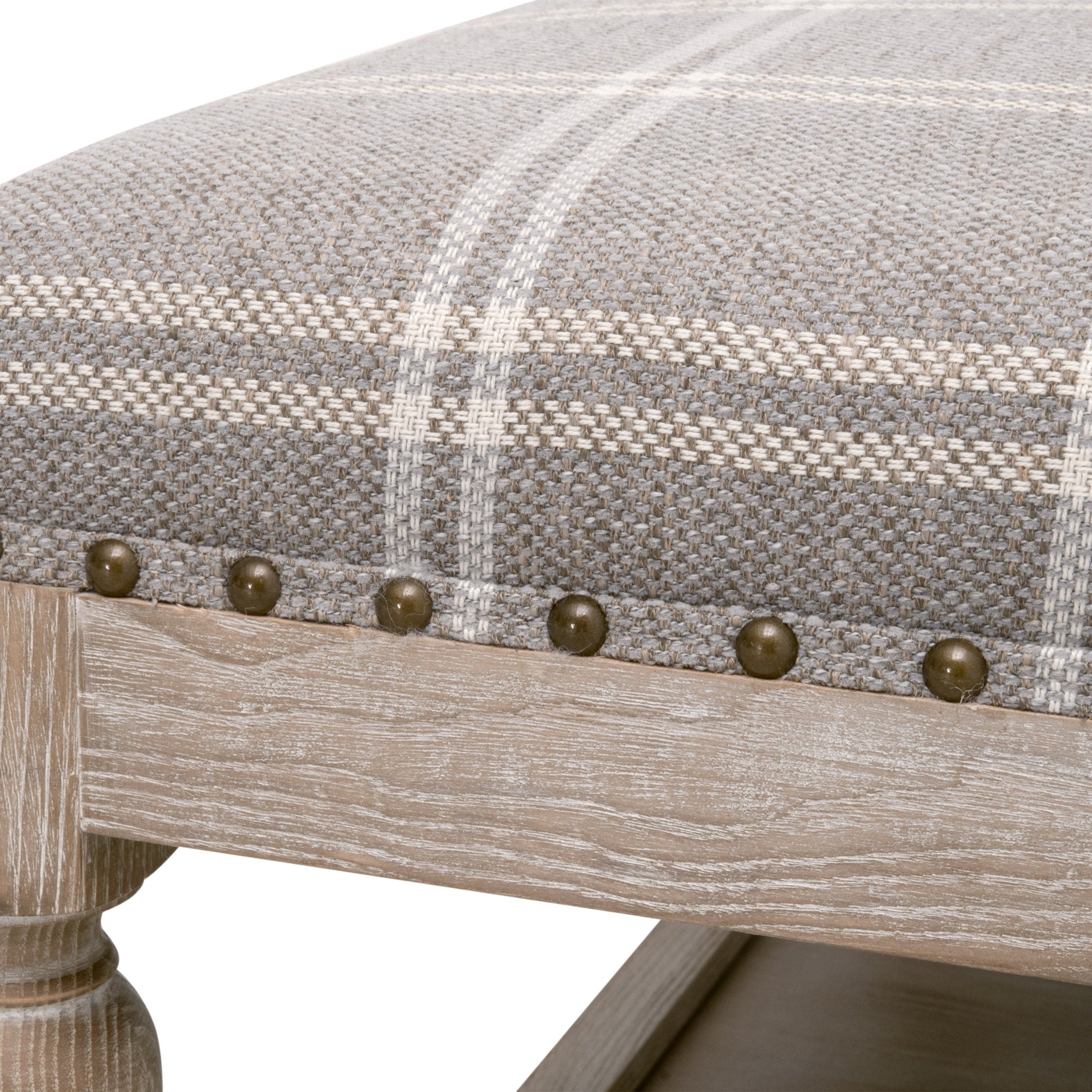 Close-up of Townsend Upholstered Coffee Table showing plaid fabric with gold nailhead trim and natural gray ash wood leg detail