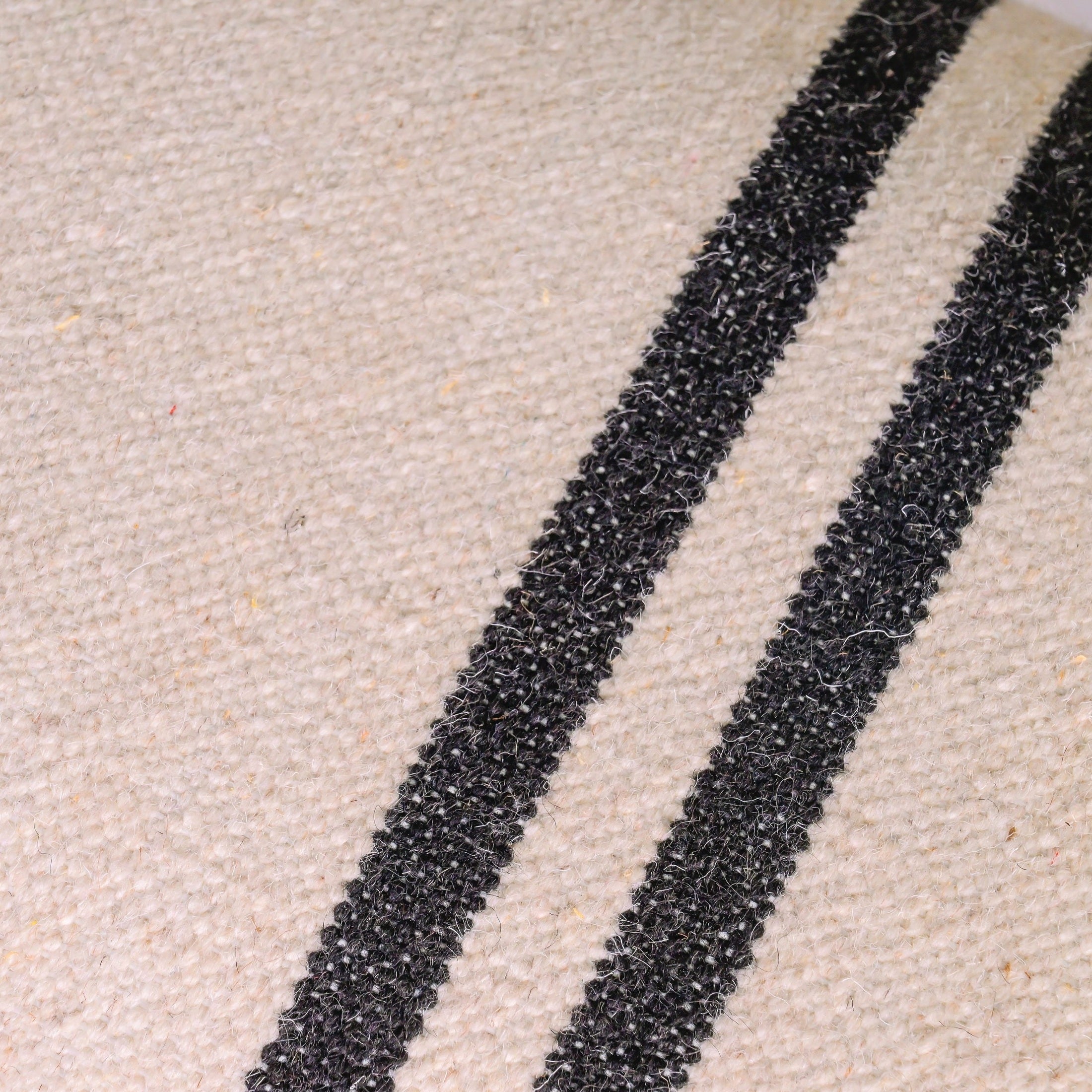 Close-up of handwoven fabric with black stripes on WULLEN BENCH upholstery by GO HOME.