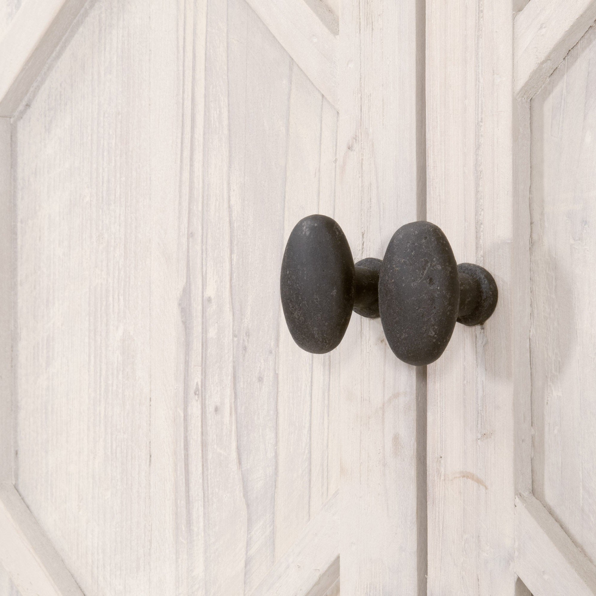 Close-up of black metal knobs on diamond-patterned whitewashed wooden cabinet doors of media sideboard
