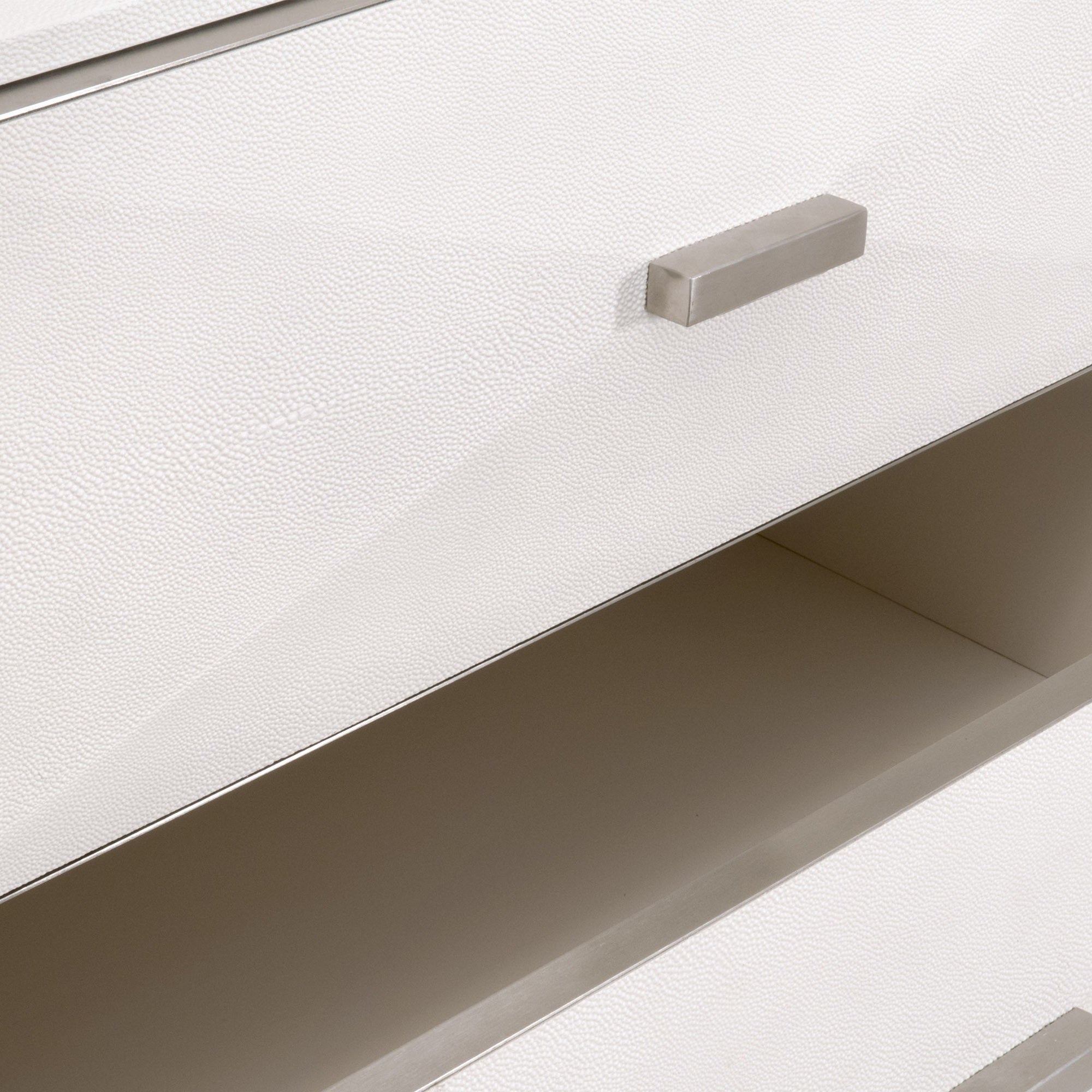Close-up of pearl faux shagreen textured drawer front with brushed stainless steel rectangular handle on dresser