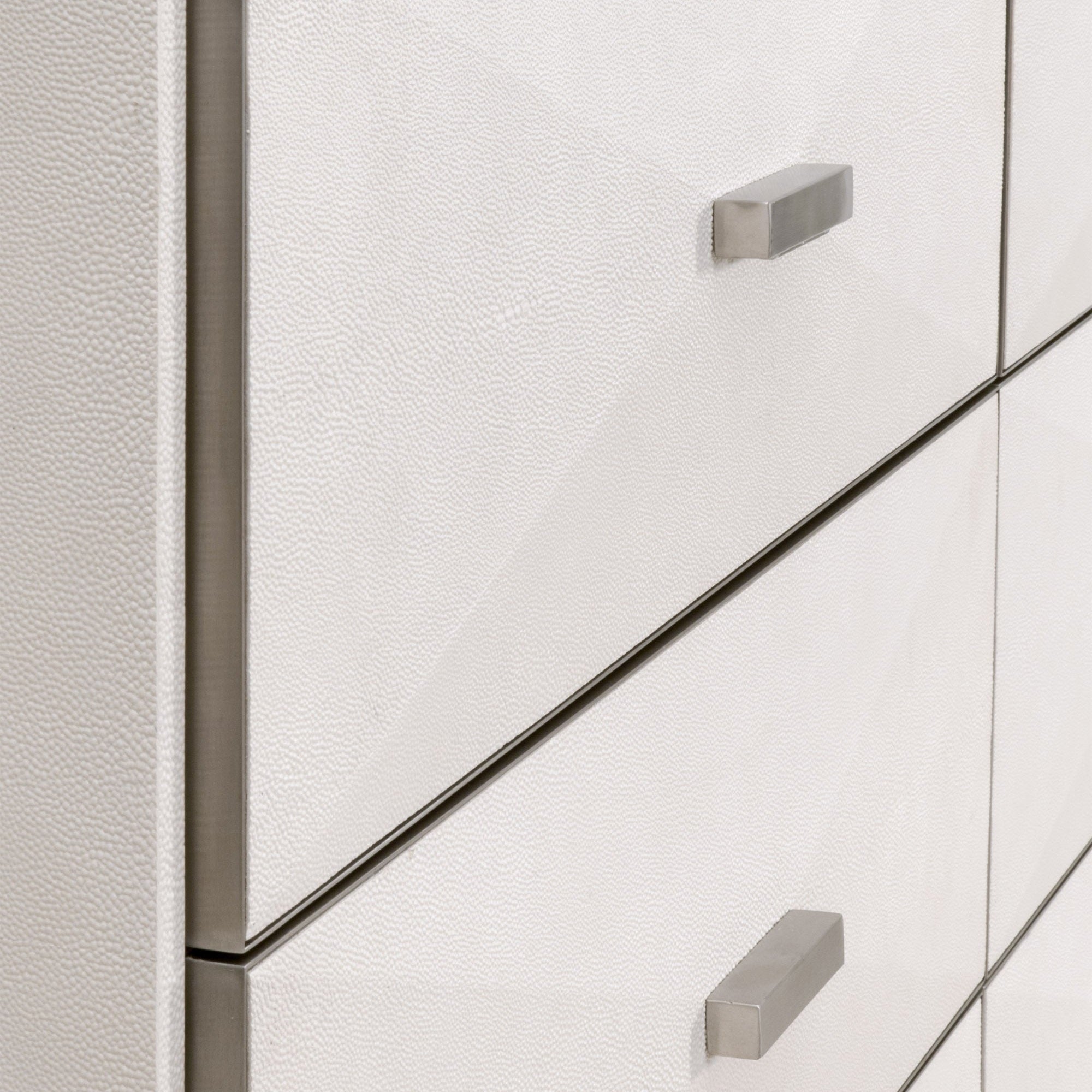 Close-up of pearl white faux shagreen resin drawer fronts with brushed stainless steel handles on luxury dresser